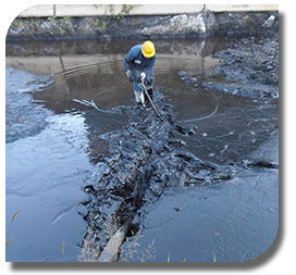 Worker placing oil booms to contain industrial spill during cleanup 