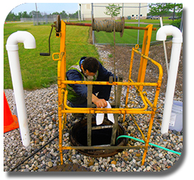 Worker above ensures the safety of partner in manhole below. 